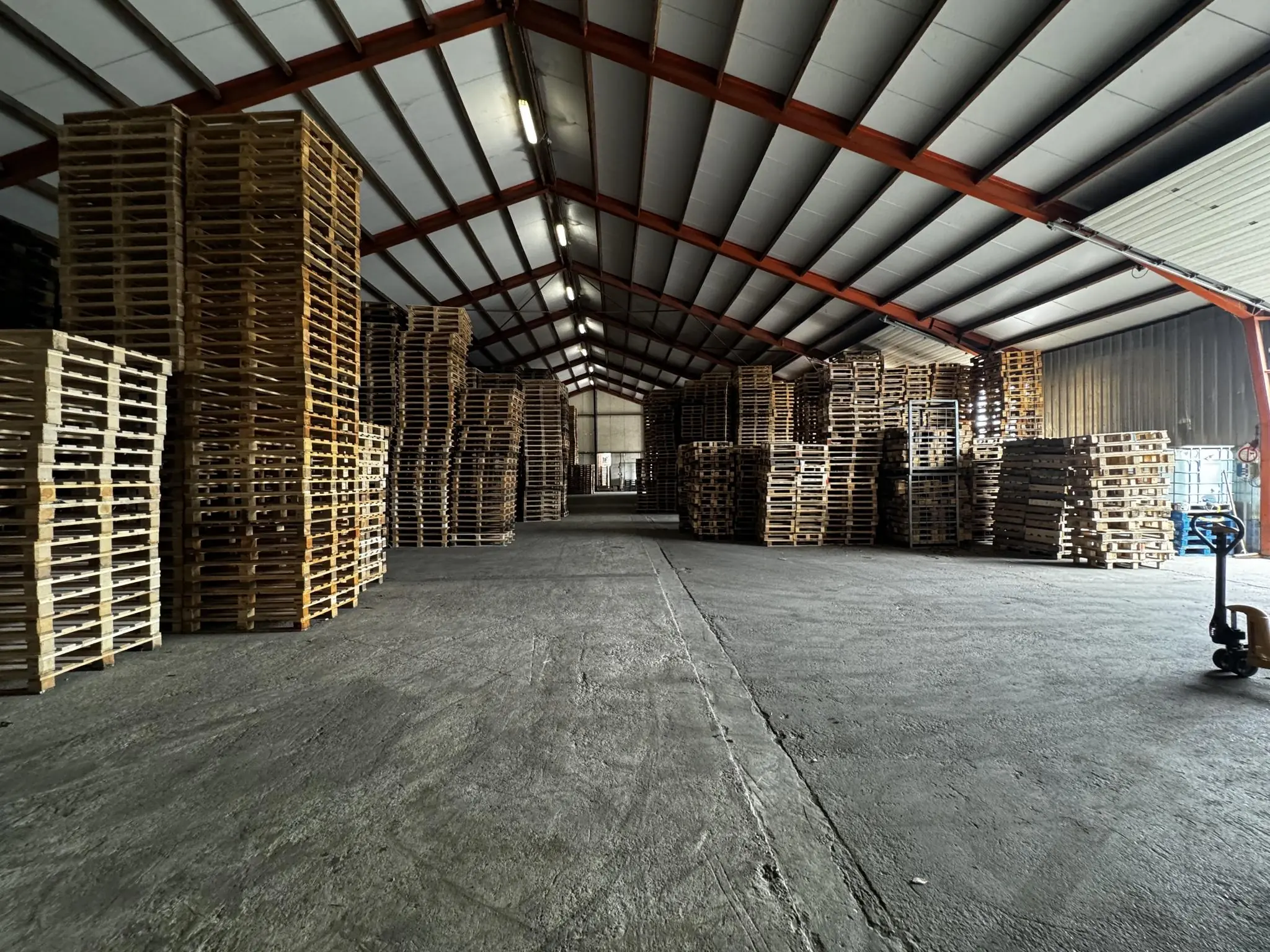 Hoge stapels houten pallets in een ruime loods aan de Graaf van Lynden van Sandenburgweg.
